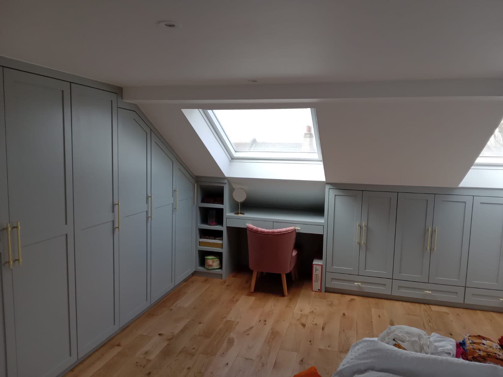 Finished sage-grey fitted loft wardrobes with brass handles