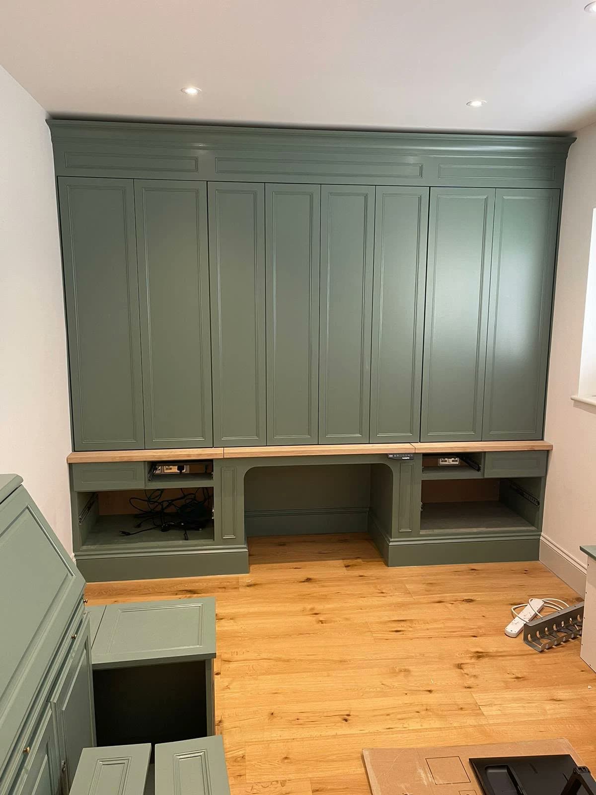 Green built-in desk and wardrobe wall with oak worktop