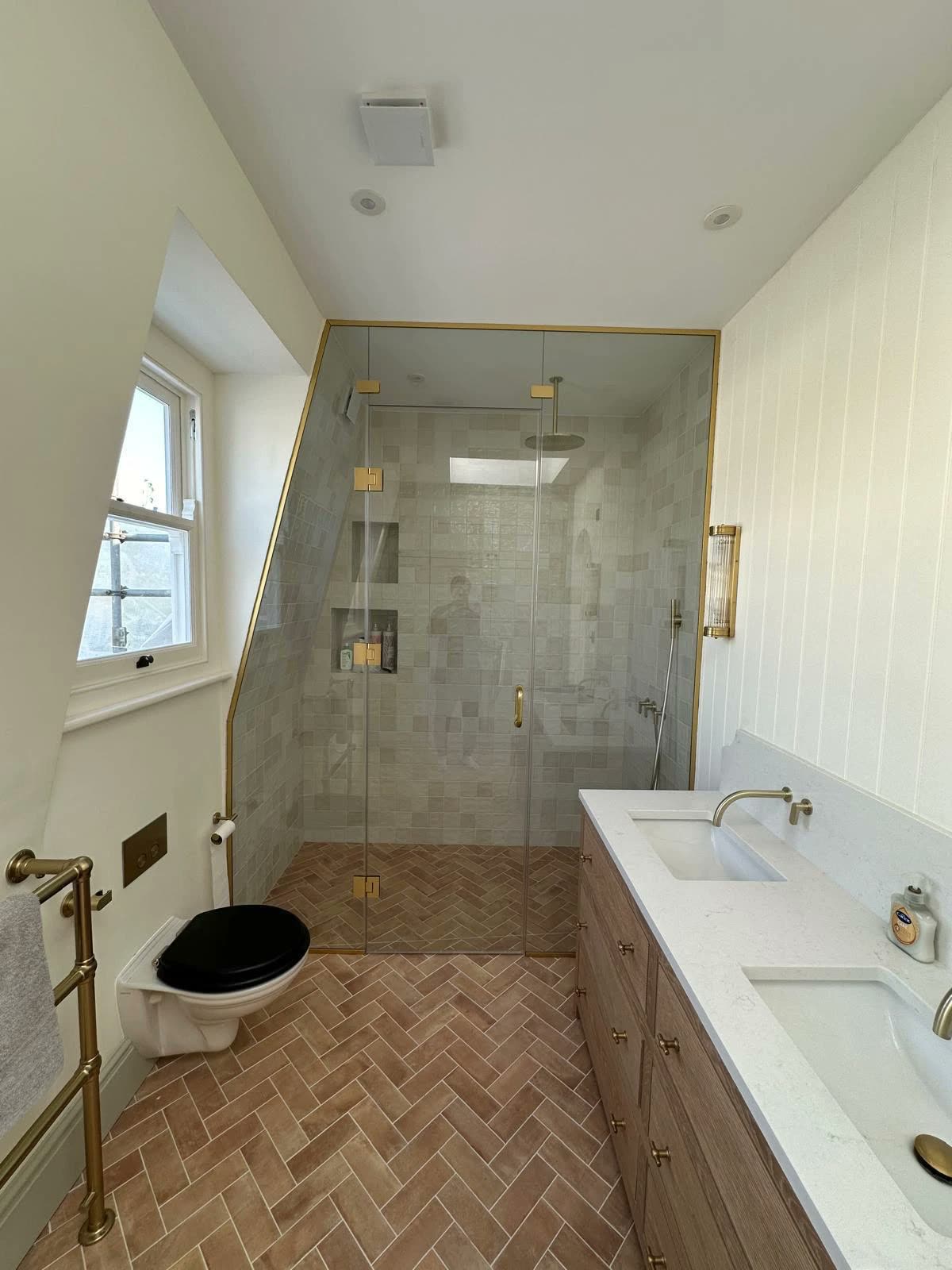 Loft bathroom with brass-framed shower and herringbone floor