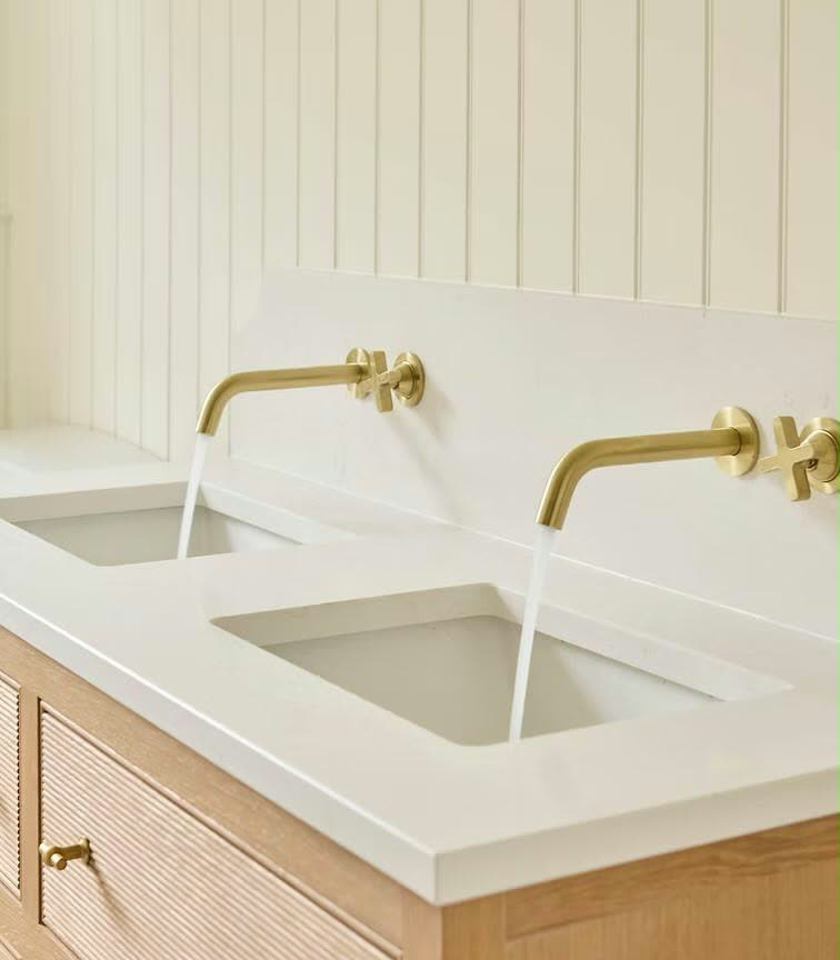 Brass wall taps running over a stone double vanity