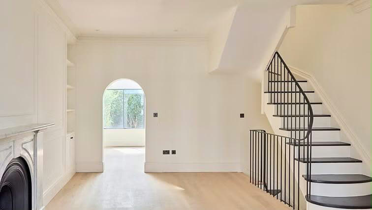 Renovated period living room with arched doorway and curved staircase