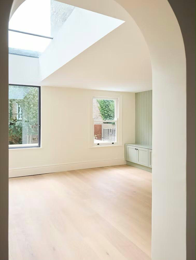 Arched doorway opening to a skylit renovated room
